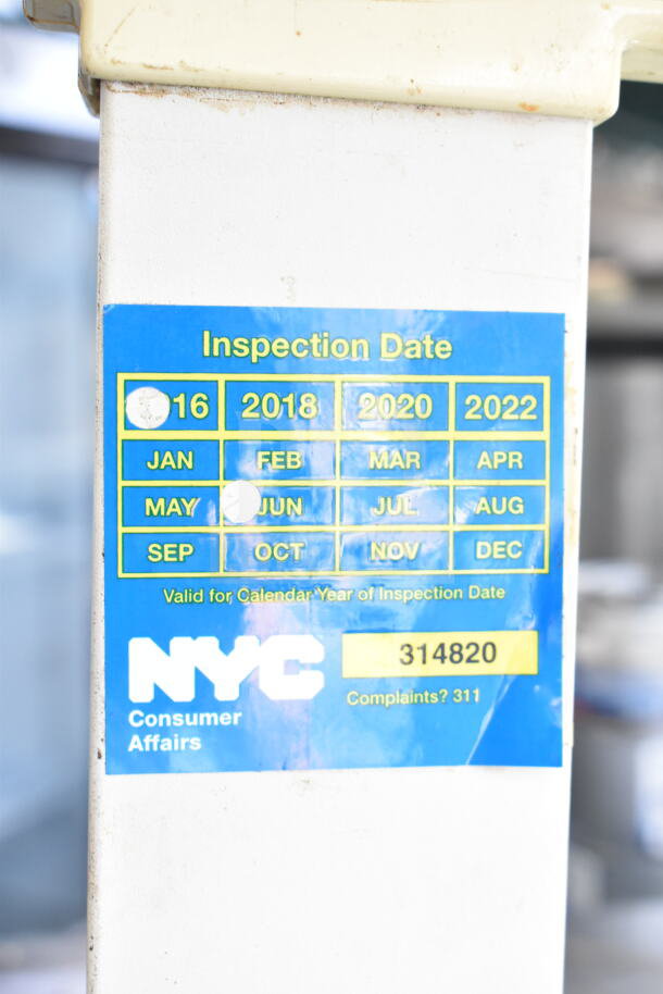 Globe GS130 commercial scale with 30-pound capacity; inspection sticker shows dates and NYC Consumer Affairs info.