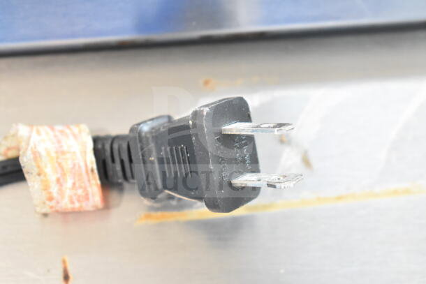 Close-up view of a power plug for a Sharp EL-1197PIII calculator, showing prongs and wrapped label.