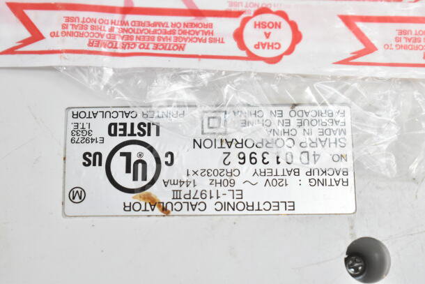 Sharp EL-1197PIII printing calculator label with UL listing. Model and battery specs visible, slight discoloration.