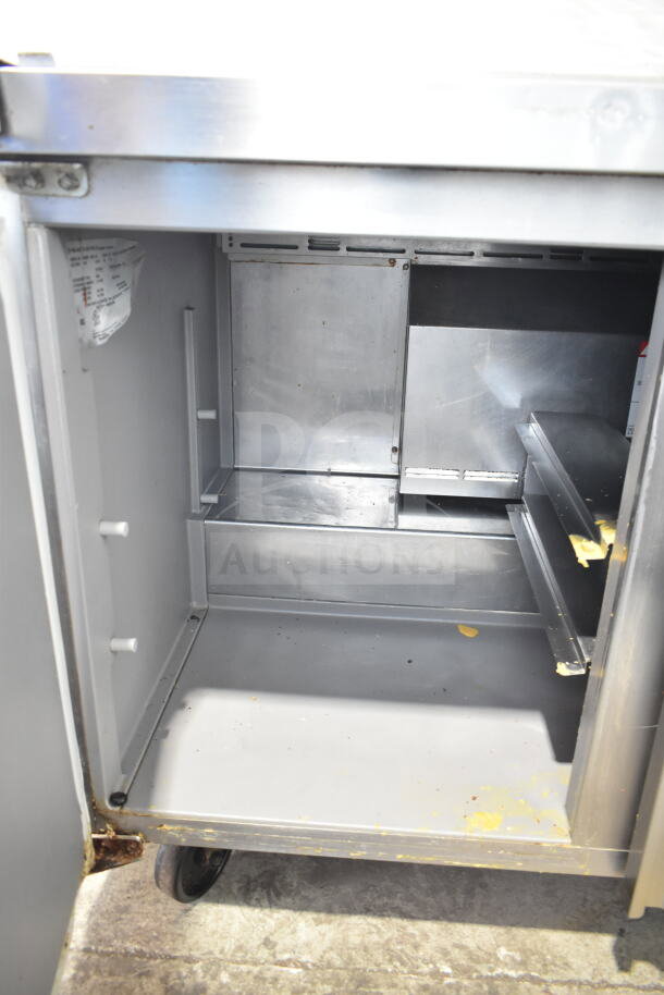 Delfield 4448NP-18M-A5 commercial prep table interior close-up. Visible shelving and signs of wear. 115V, 1 Phase.
