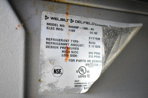 Tag on Delfield 4448NP-18M-A5 prep table shows model, electrical requirement, and refrigerant type R290. NSF certified.