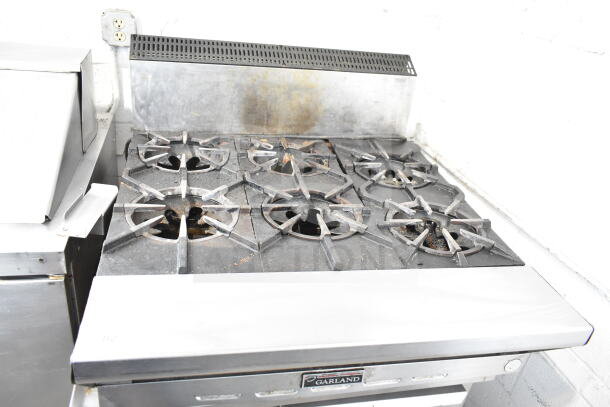 Garland commercial countertop gas 6 burner range in used condition. Features six cast iron burners, stainless steel construction, Garland logo on front.