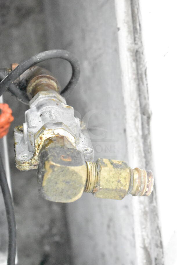 Alt text: Close-up of a gas valve connection, part of a Garland Commercial Gas Range, showing wear and patina.