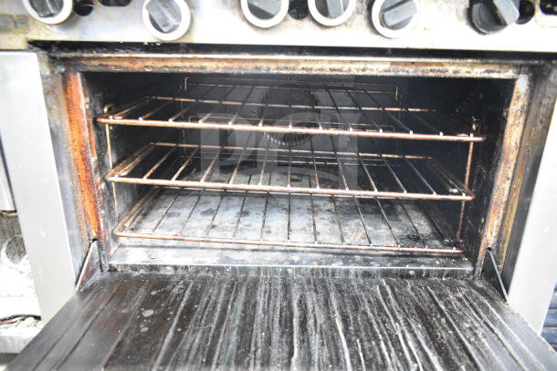 Garland commercial gas-powered 6 burner range with convection oven, showing interior and racks with noticeable wear.