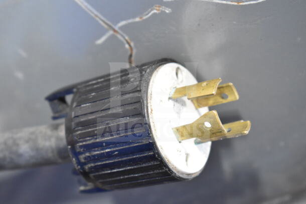 Close-up of the power plug for a Hobart M 802 Commercial Mixer, showing three brass prongs and a black plastic housing.