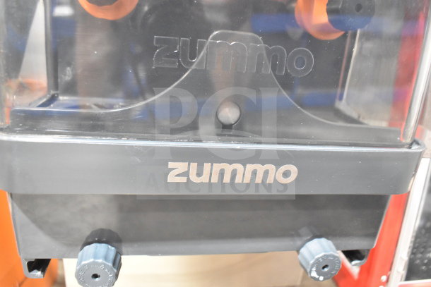 Zummo Z06C-N commercial juicer, black with orange accents. Visible branding, used condition. Model suitable for 100-120V, 1 phase.