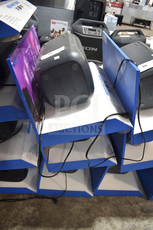 3 store display shelves containing Onn medium party speakers, each with cords. Display in good condition.