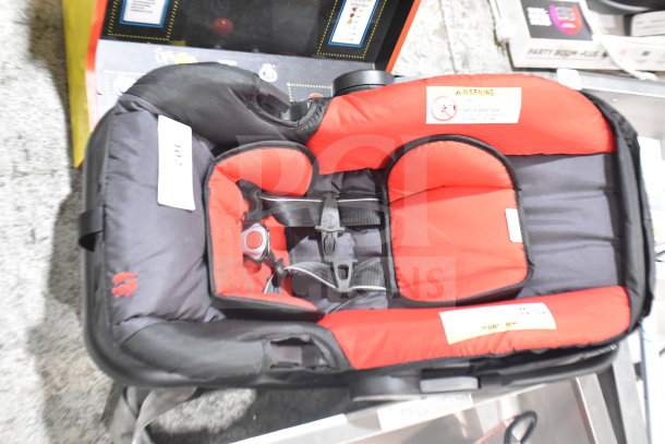 Babytrend infant car seat with base, red and black design. Features adjustable harness and safety labels. Excellent condition.