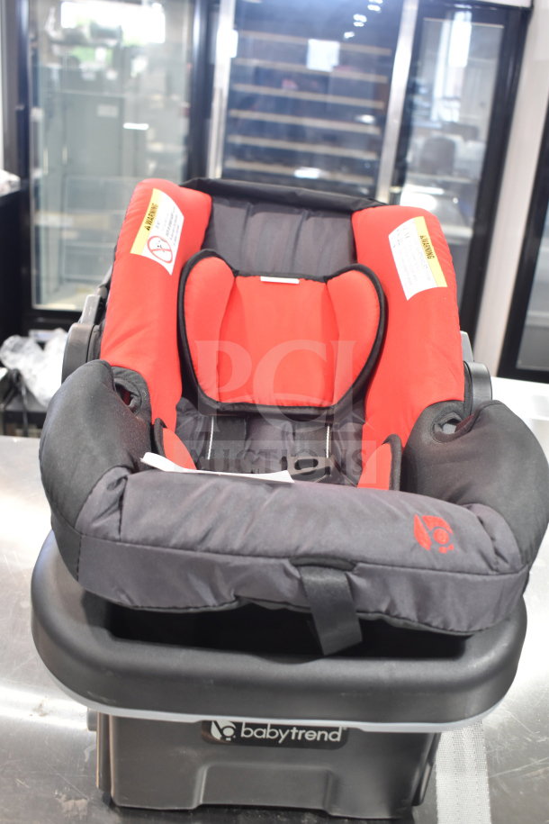 Babytrend infant car seat with base, red and black, in excellent condition. Safety warnings visible on seat fabric.