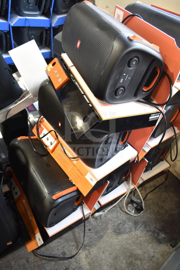 3 JBL Partybox 110 speakers on store display, black with orange accents. Visible controls and labels. Good condition.
