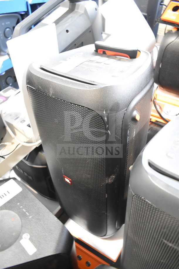 JBL speaker in store display, black with visible logo, slight wear, featuring handle and control buttons on top.