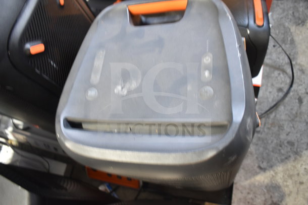 Dual store display with JBL speaker, black and orange, showcasing light wear. Includes handle and visible buttons.
