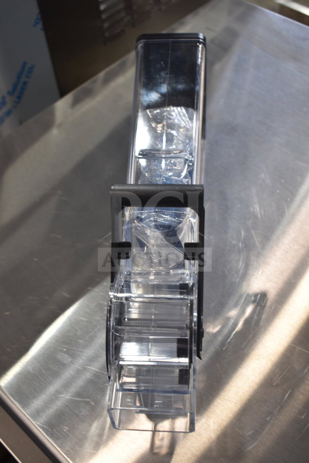Brand new scratch and dent dry goods dispenser, transparent, with black accents, on a metal surface.