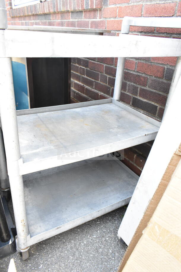 Gray poly 3 tier cart with commercial casters, showing some wear; sturdy for heavy-duty use.