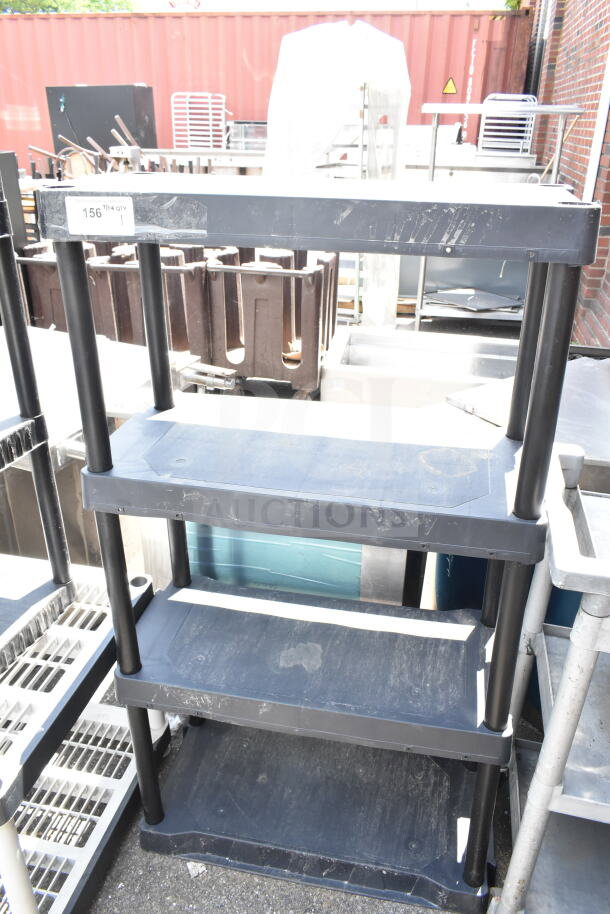 Black Poly 4 Tier Shelving Unit, durable plastic, light surface wear, detachable design, label reads "156 7/ñ QTY 1".
