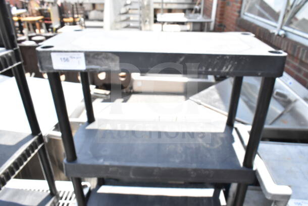 Black Poly 4 Tier Shelving Unit, used condition, showing slight wear. Sturdy design for storage efficiency.