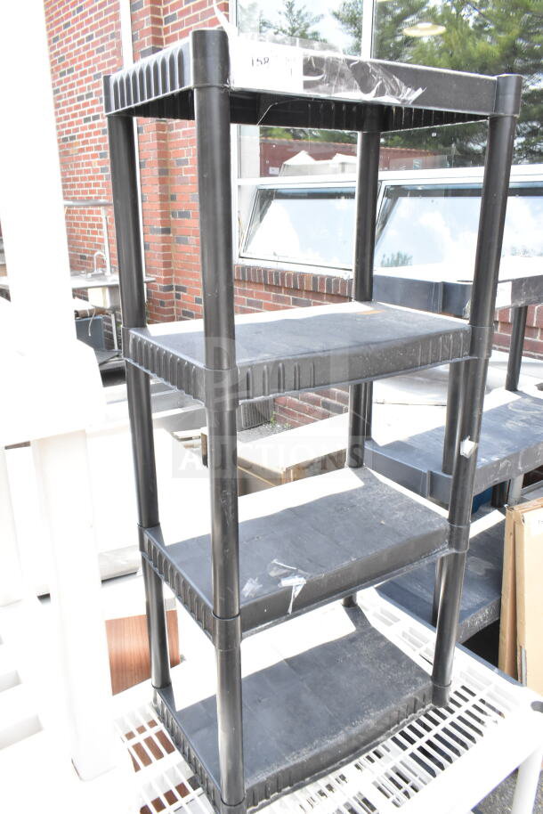 Black poly 4 tier shelving unit with sturdy shelves and robust construction. Slight surface dust present. Suitable for storage.
