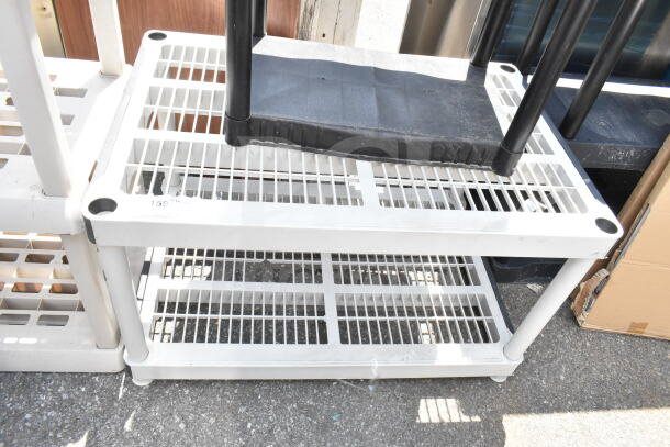 Gray poly 2-tier shelving unit, sturdy construction, slatted design, minor scuffs, ideal for storage.