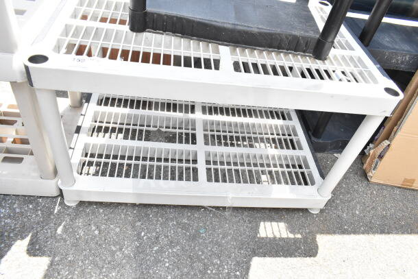 Gray poly 2-tier shelving unit with vented design, sturdy legs, and moderate wear. Ideal for storage and organization.