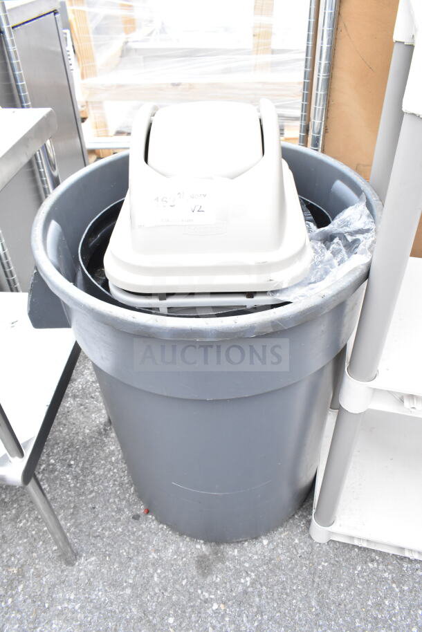 Two gray trash cans, one inside the other, with white lid. Slight wear. Rubbermaid label visible. Auction for two units.