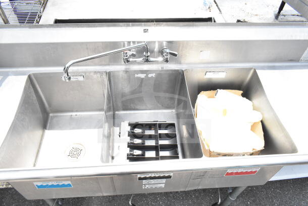 Duke Commercial 3 bay sink with dual drain boards, chrome faucet, and handles. Stainless steel, good condition, ideal for kitchens.
