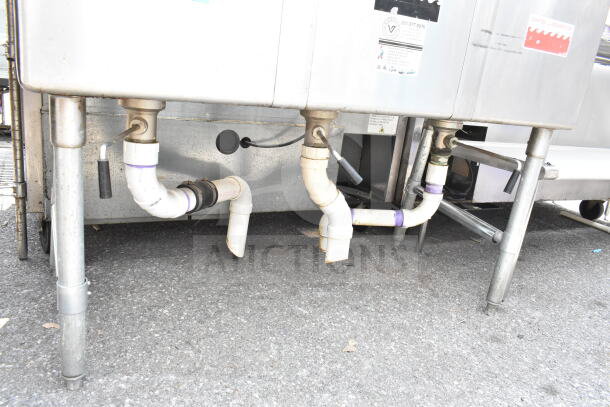 Commercial Duke 3 bay sink with dual drain boards, functional faucet, and handles. Visible piping and sturdy metal legs.
