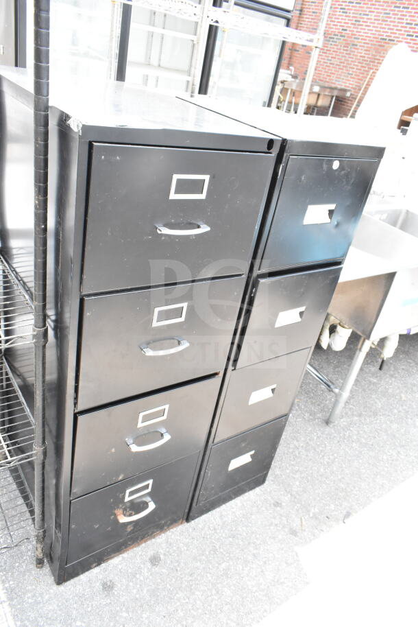 Two black 4-drawer filing cabinets with metal handles, minor scratches, and label holders on each drawer, positioned outdoors.