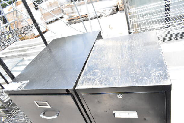 Two black 4-drawer filing cabinets with visible surface wear. Includes label and handle. Bid once for both units.