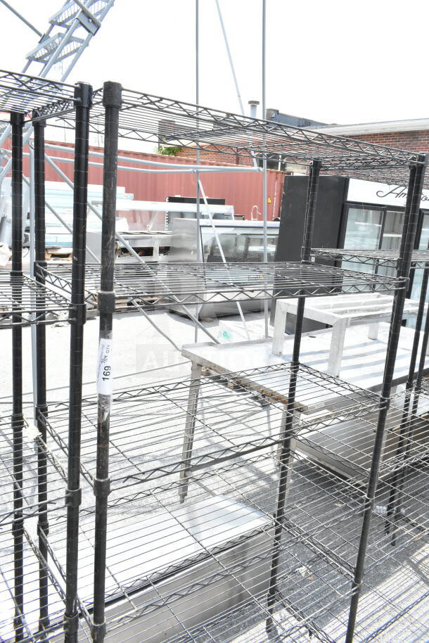 Black 6-tier wire shelving unit in fair condition. Buyer must dismantle for shipping; tag visible on the frame.