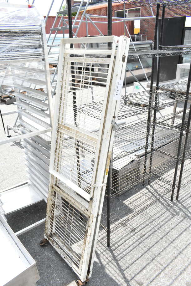 Metal storage rack with wheels, white, showing signs of rust and wear. Includes attached item tag with auction details.