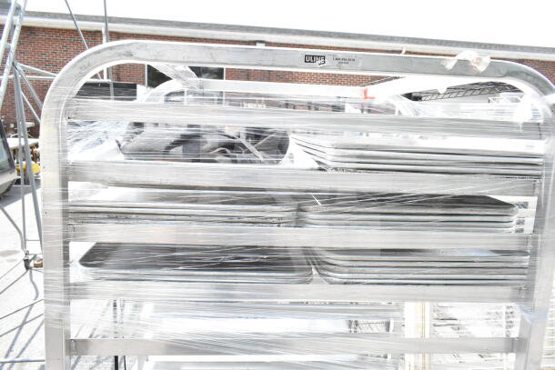 Commercial pan transport rack with sturdy metal frame, wrapped, on commercial casters. Uline label visible, good condition.