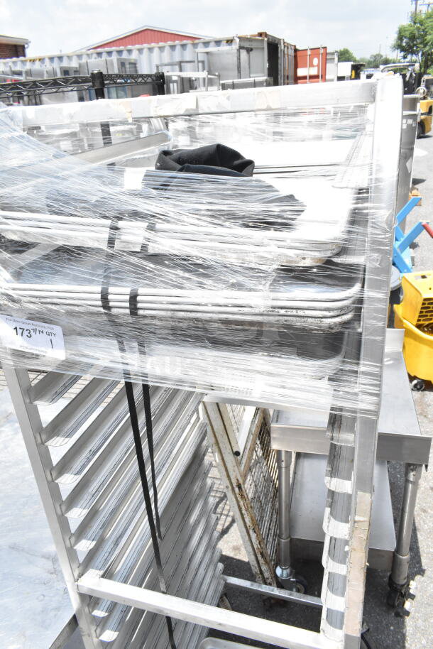Commercial pan transport rack with multiple shelves on heavy-duty casters. Wrapped in plastic, in used condition.