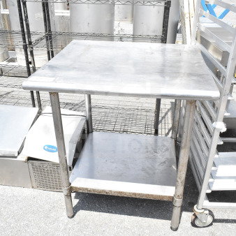 Commercial metal table with under shelf, used condition. Ideal for industrial kitchens, durable surface, and sturdy legs.