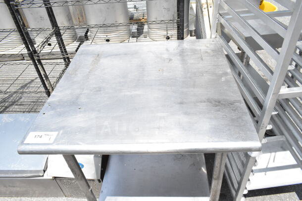 Commercial stainless steel table with under shelf, used condition, visible wear, label showing item number 174.