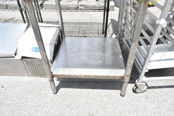 Stainless steel commercial table with under shelf, used. Visible surface wear and slight rust on legs.