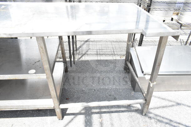 Stainless steel commercial table with two under shelves, sturdy frame, ideal for kitchen or workspace use. Slightly worn condition.