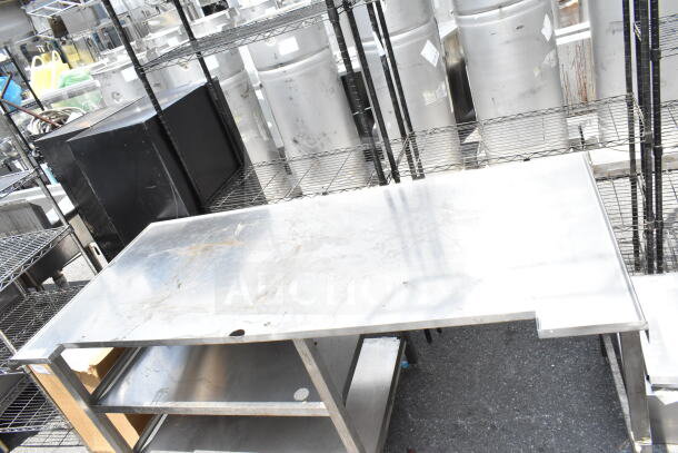 Stainless steel commercial table with two under shelves. Used condition, some surface wear visible.