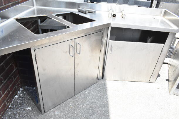 Commercial stainless steel corner work station with two cutouts, three doors, some wear; ideal for kitchen environments.