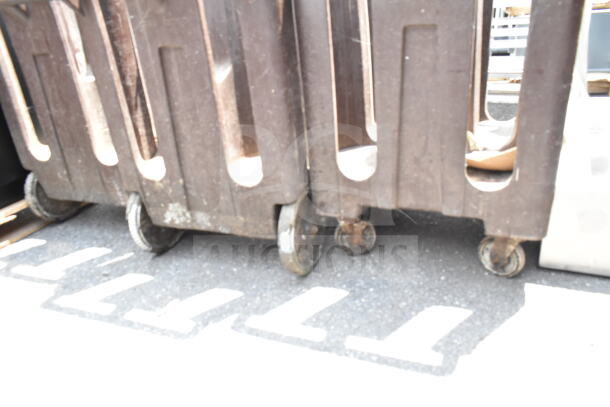 Three brown poly dish carts on commercial casters, showing signs of use, suitable for restaurant or catering purposes.
