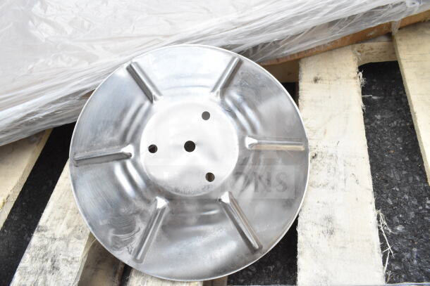 Metal lid on wooden pallet, part of new scratch and dent auction items. Features holes and ribbed design.