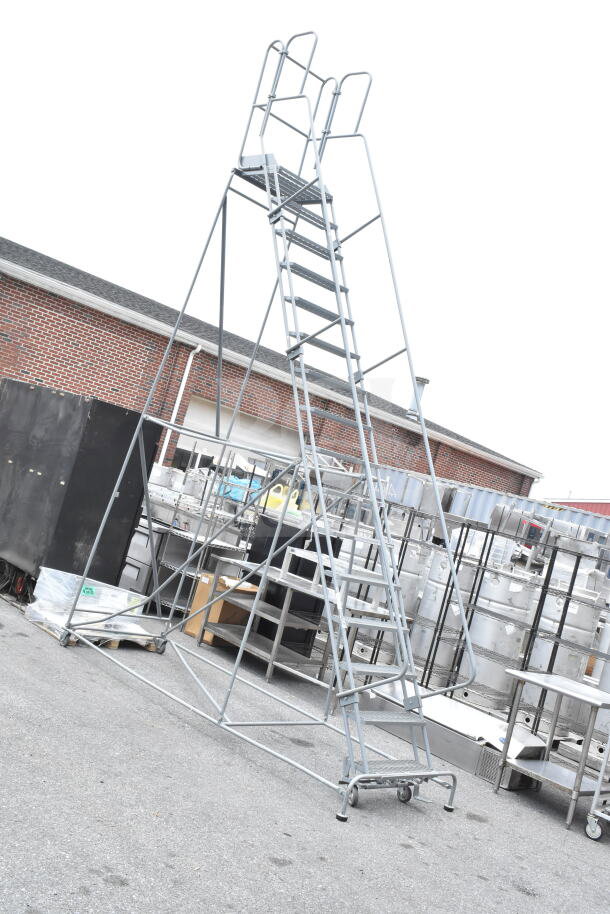 Gray portable ladder steps with multiple tiers, sturdy metal frame, safety handrails, and wheels for easy mobility. Suitable for industrial use.