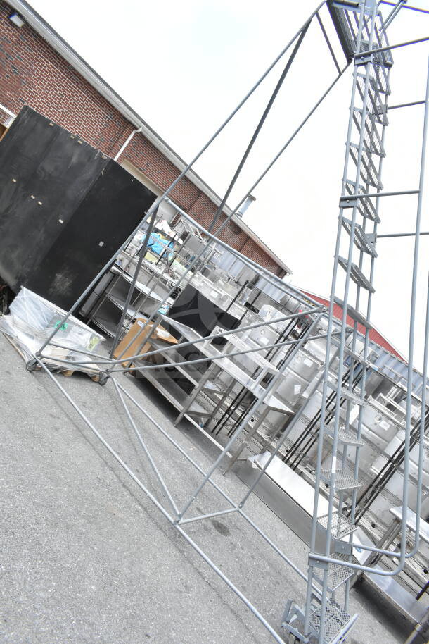 Gray portable ladder steps with metal frame, in good condition. Sturdy design, ideal for industrial or warehouse use.