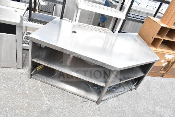 Commercial stainless steel table with two under shelves. Includes cable management hole. Slight wear visible.