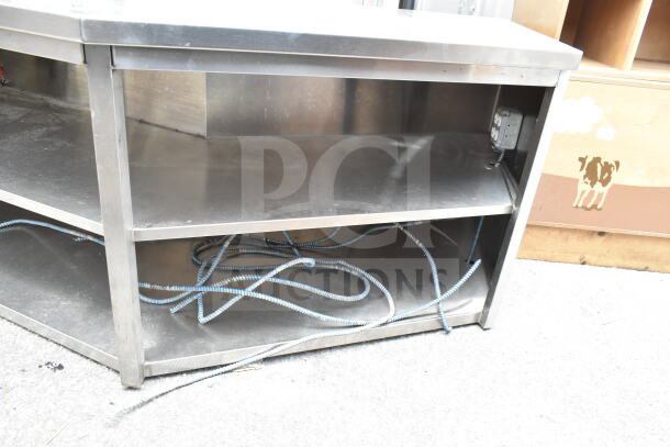 Commercial stainless steel table with two under shelves, good condition, visible wiring underneath.