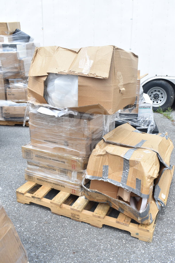 Stack of boxes on a pallet showing brand new, scratch and dent items, including tables and knock down hood, partially wrapped and some open, indicating condition.