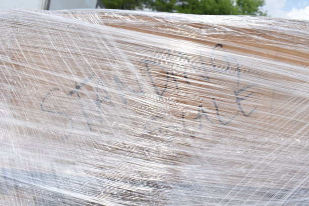 Pallet wrapped in plastic labeled "STANDING SALE," contains 15 scratch and dent items including chairs.