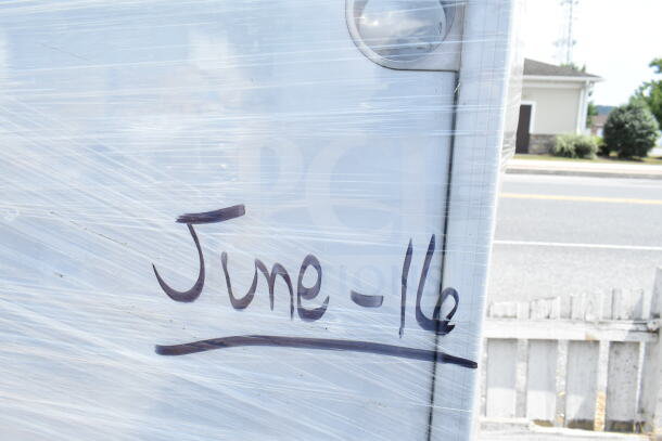 Auction item wrapped in plastic with "June-16" written on it; includes new scratch and dent work table, seafood boiler cart.