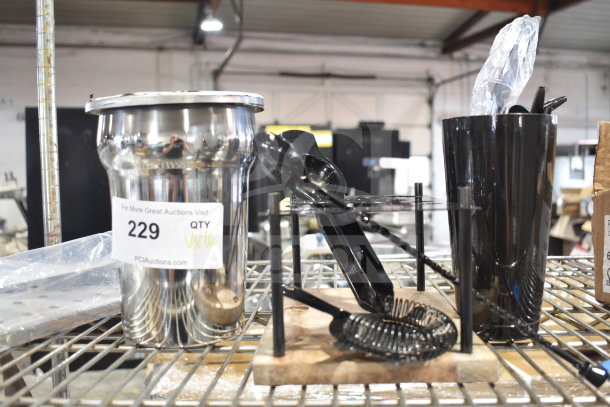 16 brand new drinkware items including a cylindrical bin, pourers, and stirring spoon. Auction tag indicating lot 229, quantity 16.
