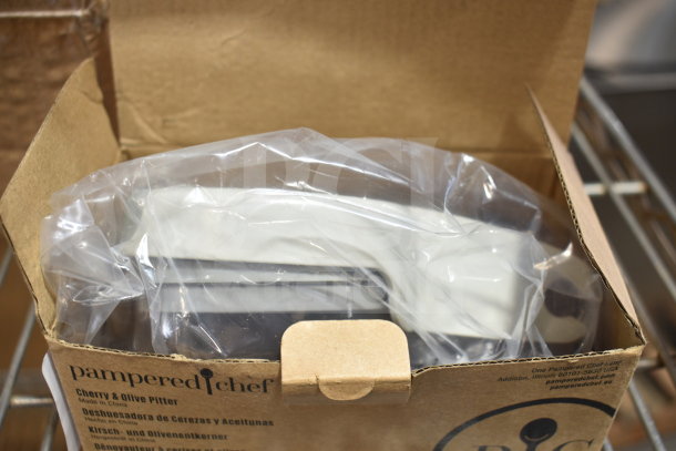 Pampered Chef cherry and olive pitter, model 100353, in original packaging, new condition, label visible.