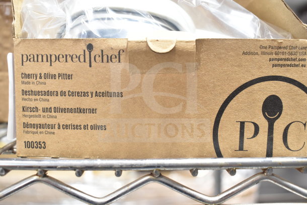 Pampered Chef Cherry & Olive Pitter, model 100353, new in box. Packaging shows "Made in China" and multiple languages.